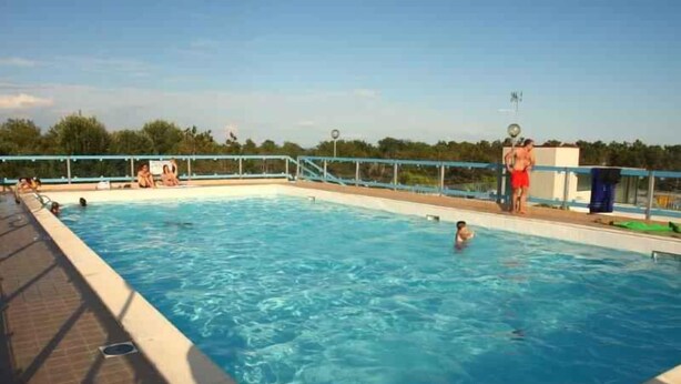A swimming pool with a tiled deck, a lifeguard tower, and a clear sky. - Holiday apartment mit Klimaanlage und Balkon (Bibione)