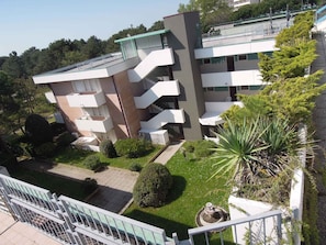 Un edificio de varios pisos con balcones, un jardín y una piscina.