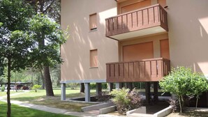 A multi-story building with balconies, a lawn, and trees. - Holiday apartment mit Klimaanlage und Balkon (Bibione)