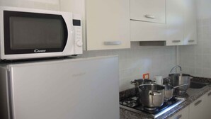A kitchen with a microwave, a refrigerator, a stove, and pots. - Holiday apartment mit Klimaanlage und Balkon (Bibione)