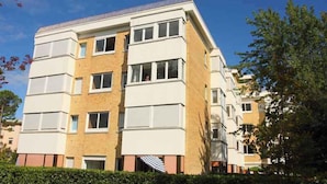 A multi-story residential building with a brick facade, multiple windows, and a flat roof. - Holiday apartment near the sea (Bibione)