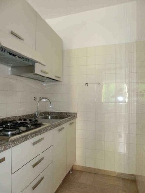 A kitchen with white cabinets, a gas stove, a sink, and a tiled backsplash.