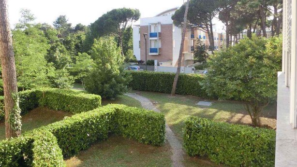 A residential building with a pathway surrounded by neatly trimmed hedges and trees. - Holiday apartment near the sea (Bibione)