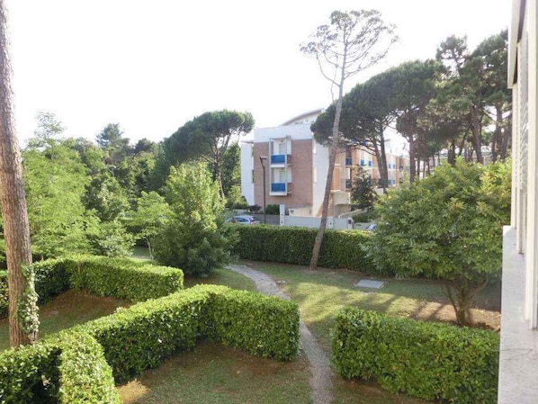 A residential building with a pathway surrounded by neatly trimmed hedges and trees.