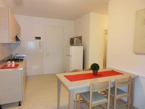 Une cuisine compacte comprenant un coin repas, un réfrigérateur et un four à micro-ondes.