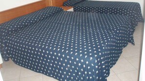 Una habitación con dos camas, cada una con cubrecama estampado con motivos de estrellas, cabecero de madera y lámpara de pared.