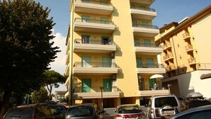 A multi-story residential building with balconies, a parking area, and a clear sky. - Holiday apartment mit Klimaanlage und Balkon (Bibione)