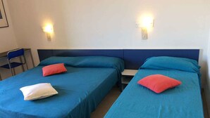 Two single beds with blue bedding and red pillows, a chair, and wall-mounted lights. - Holiday apartment mit Klimaanlage und Balkon (Bibione)