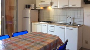 A compact kitchen with white cabinets, a microwave, a gas stove, and a sink. - Holiday apartment mit Klimaanlage und Balkon (Bibione)