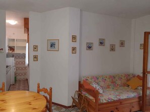 Un espacio habitable compacto con una mesa de comedor, un sofá y una zona de cocina.