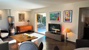 Een moderne woonkamer met een open haard, een televisie en kunstwerken aan de muur.