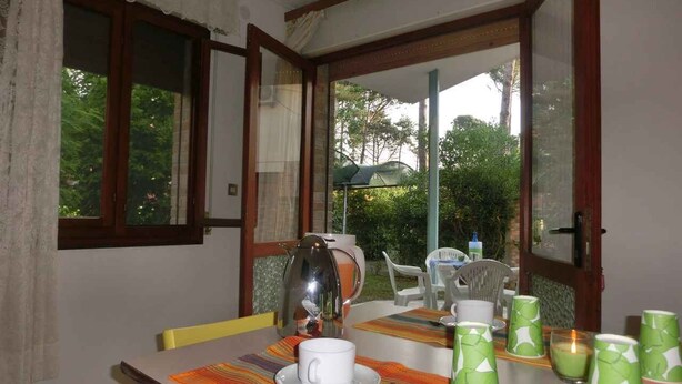 Un coin repas avec une table dressée pour deux personnes, une cafetière et plusieurs tasses vertes.
