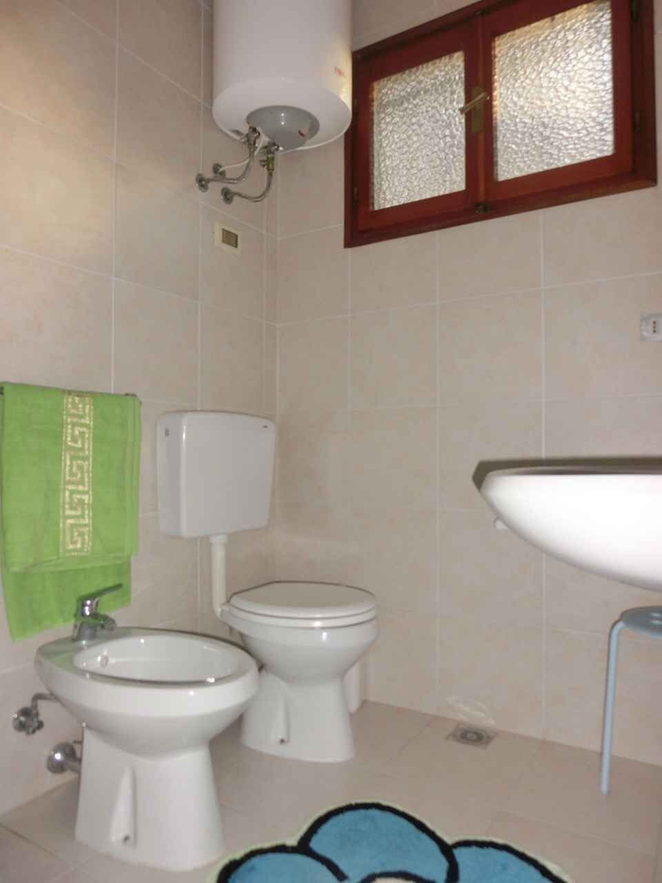A bathroom with two toilets, a sink, and a shower.