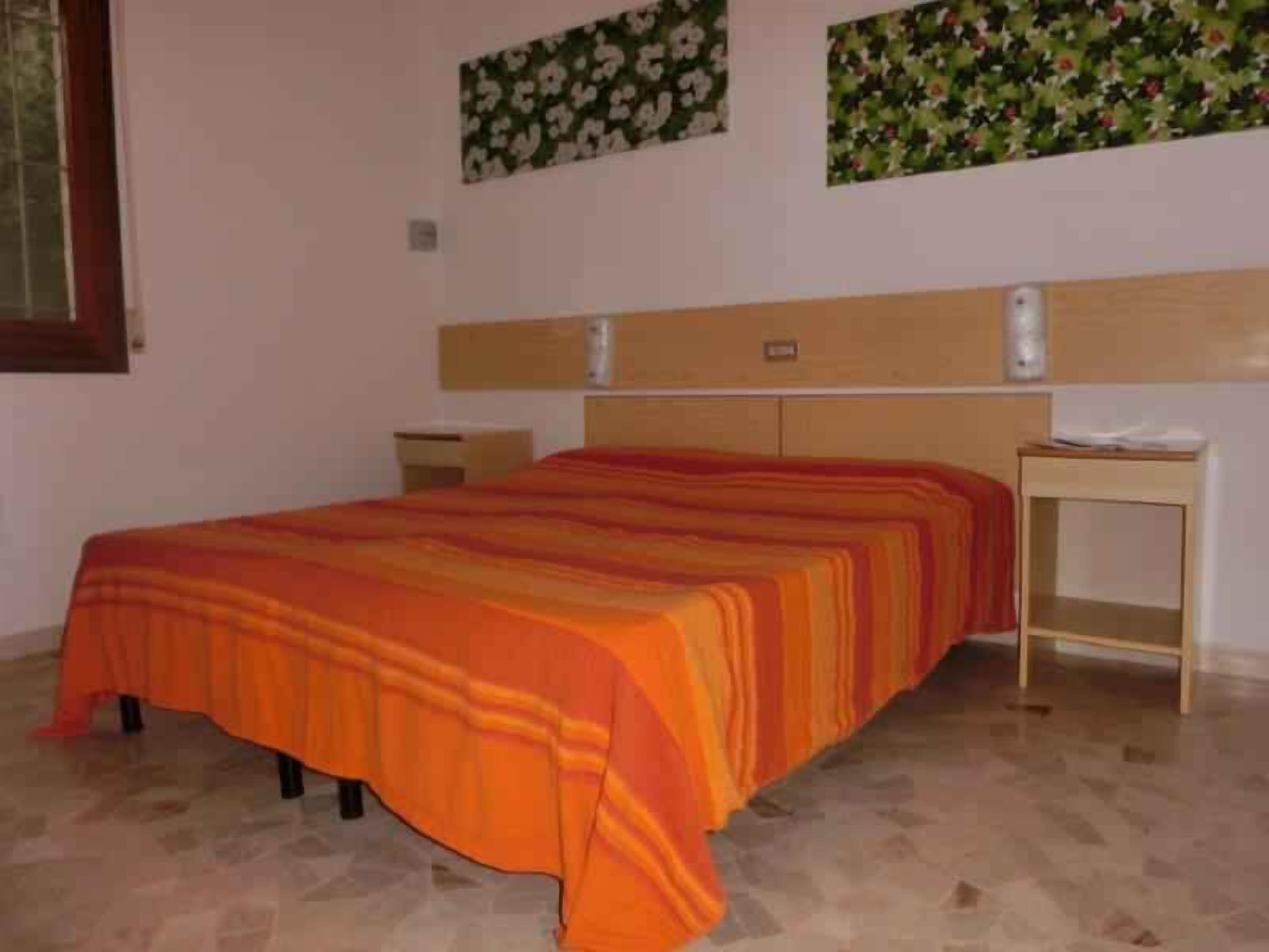 Une chambre à coucher comprenant un lit, une table de chevet, une tête de lit et des motifs floraux décorant le mur.