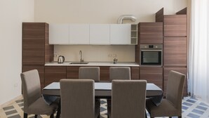 Une cuisine moderne avec un coin repas, comprenant un îlot central, des placards intégrés et une grande fenêtre.