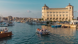 A marina with boats docked and a large building with classical architecture in the background. - Casa Darsena with Sea View Balcony by Wonderful Italy (Siracusa)