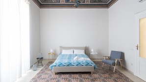 A bedroom with a bed, a chair, a nightstand, and a decorative ceiling. - Casa Darsena with Sea View Balcony by Wonderful Italy (Siracusa)