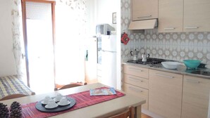 Una cocina con una mesa de comedor, sillas, estufa y refrigerador.