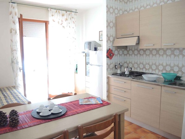 Une cuisine équipée d’une table à manger, de chaises, d’une cuisinière et d’un réfrigérateur.