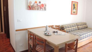 Un comedor con una mesa, sillas, una cafetera y un cuadro en la pared.