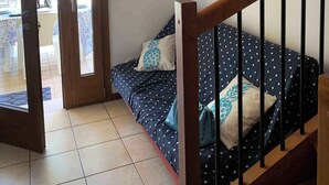 Una habitación con una cama, un cuadro, una escalera y una puerta que da a un espacio exterior.