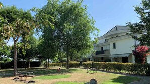 Un parque con un banco, un sendero y un edificio al fondo.