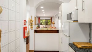 Une cuisine moderne avec des armoires blanches, un plan de travail en bois et un four à micro-ondes.