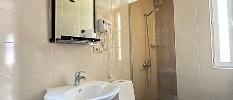 Un baño con lavamanos pedestal, inodoro, ducha y espejo.