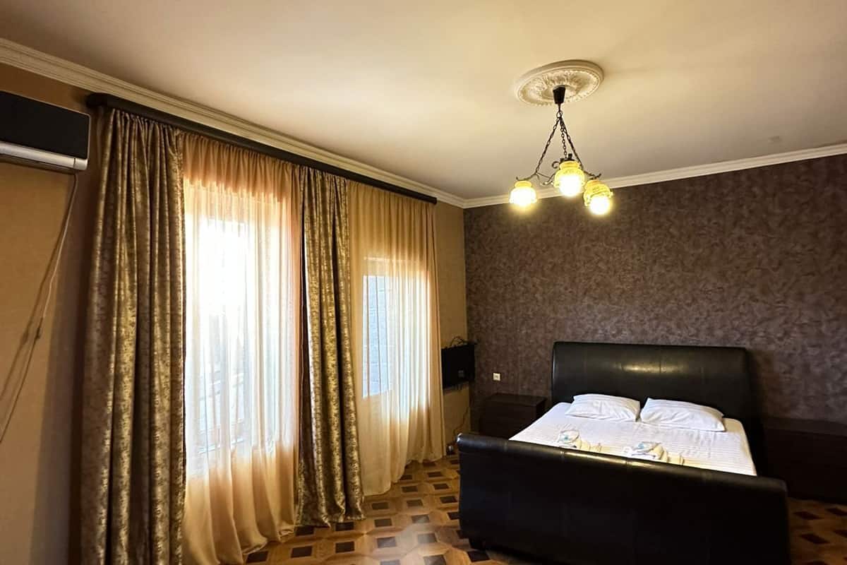A hotel room with a large bed, a patterned floor, and a ceiling light fixture.