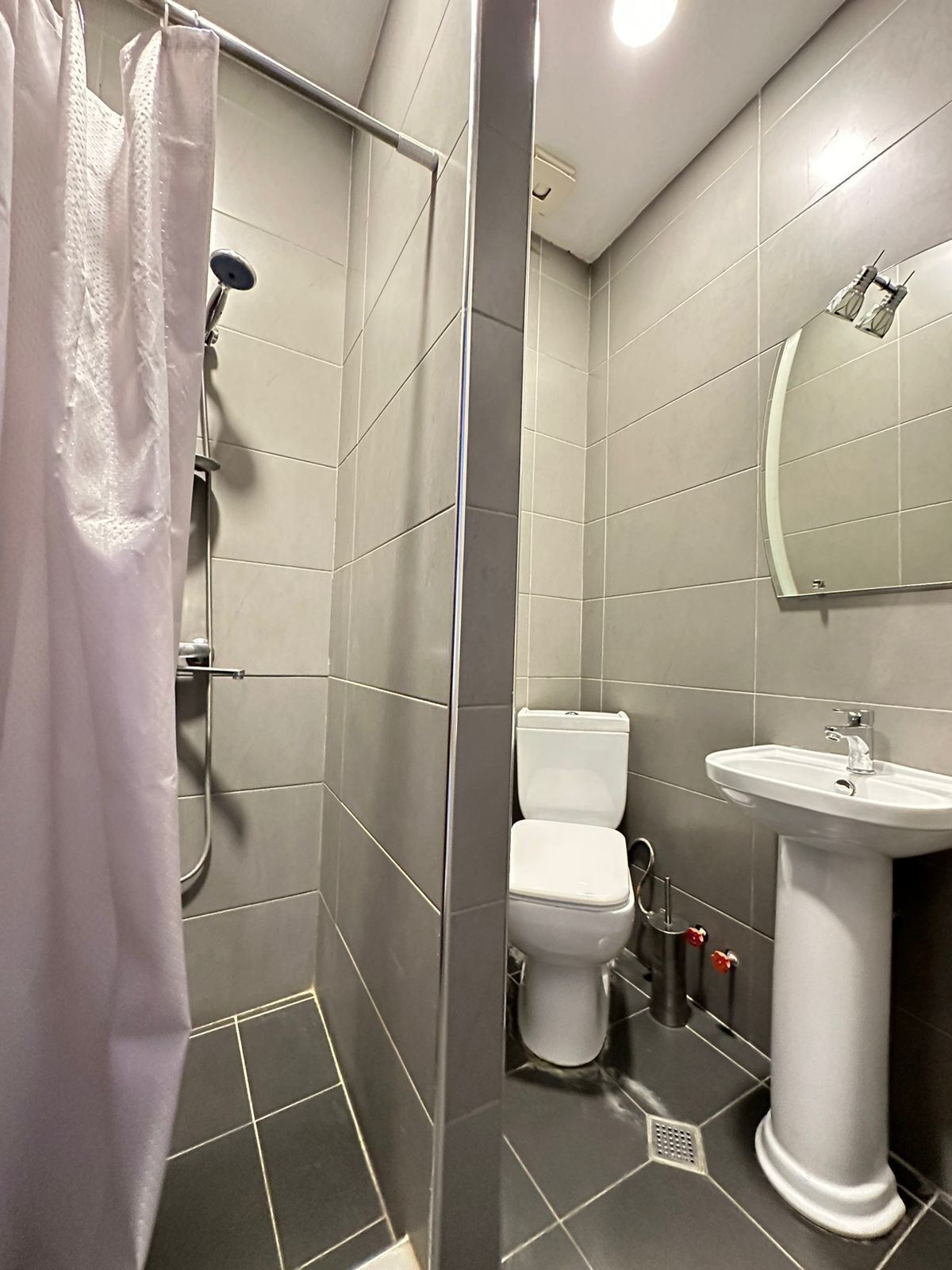 Une salle de bain moderne équipée d’une douche, de toilettes et d’un lavabo.