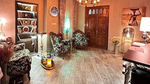 A spacious living room with a wooden floor, a chandelier, a bookshelf, and a large wooden door. - Hotel Piano (Tbilisi)