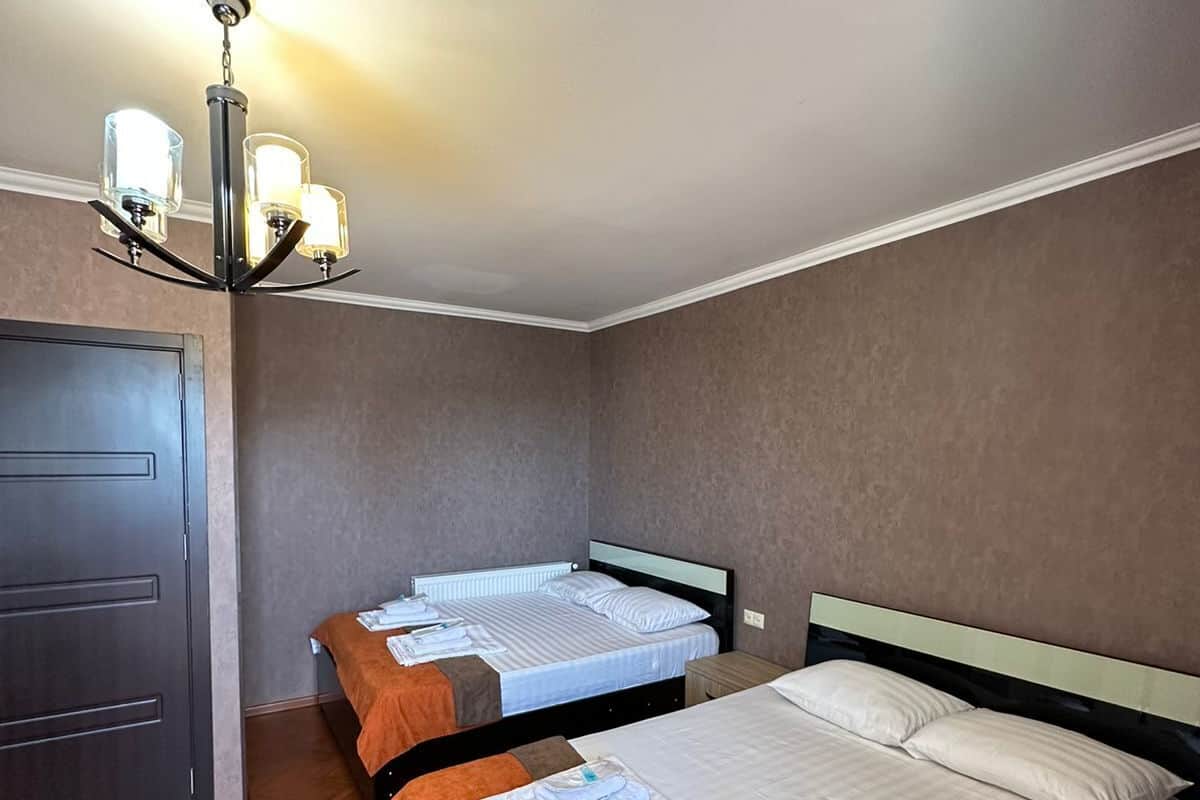 A hotel room with two beds, a wardrobe, and a chandelier.