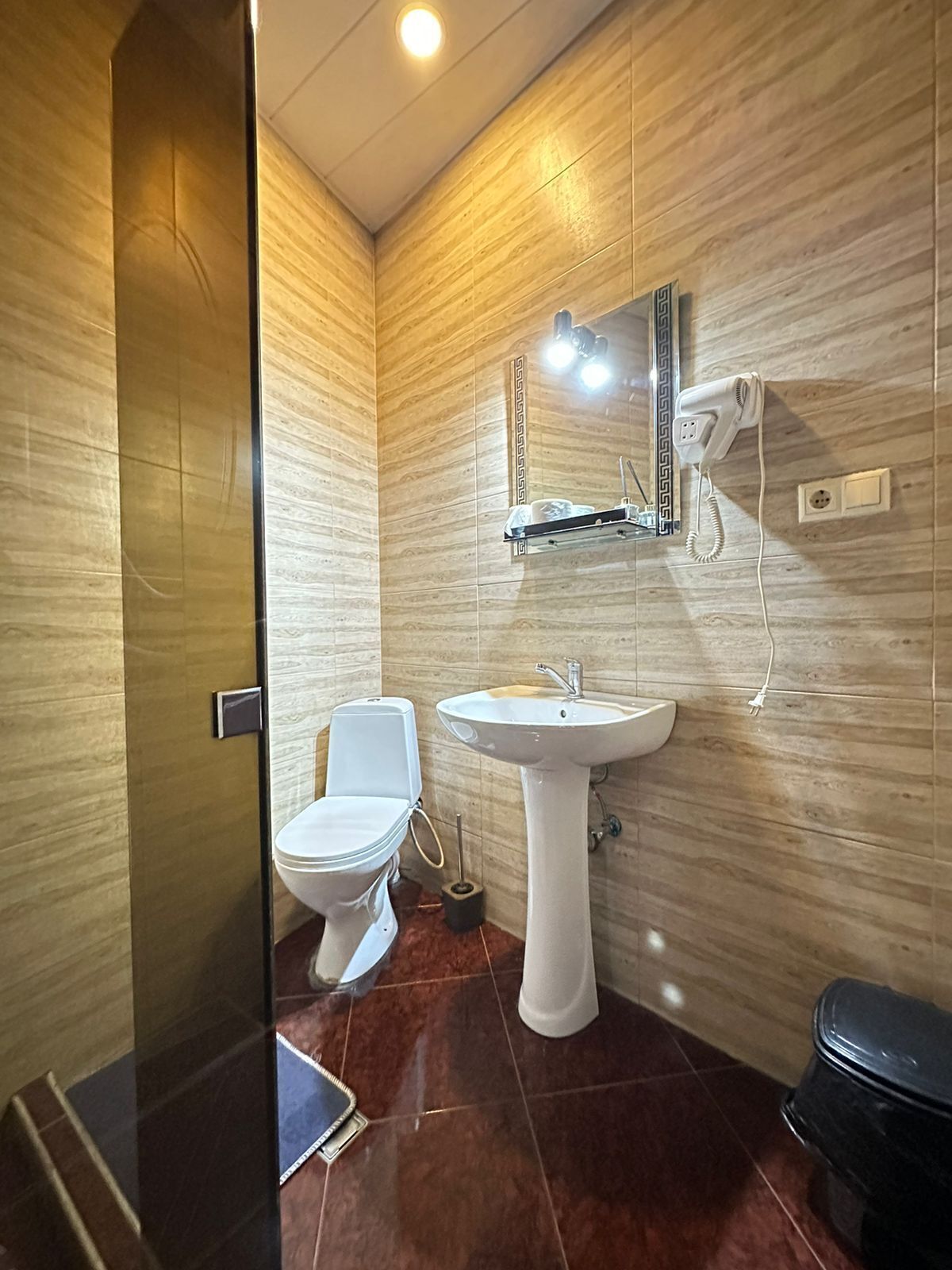 Casa de banho com sanita, lavatório e espelho com telefone.