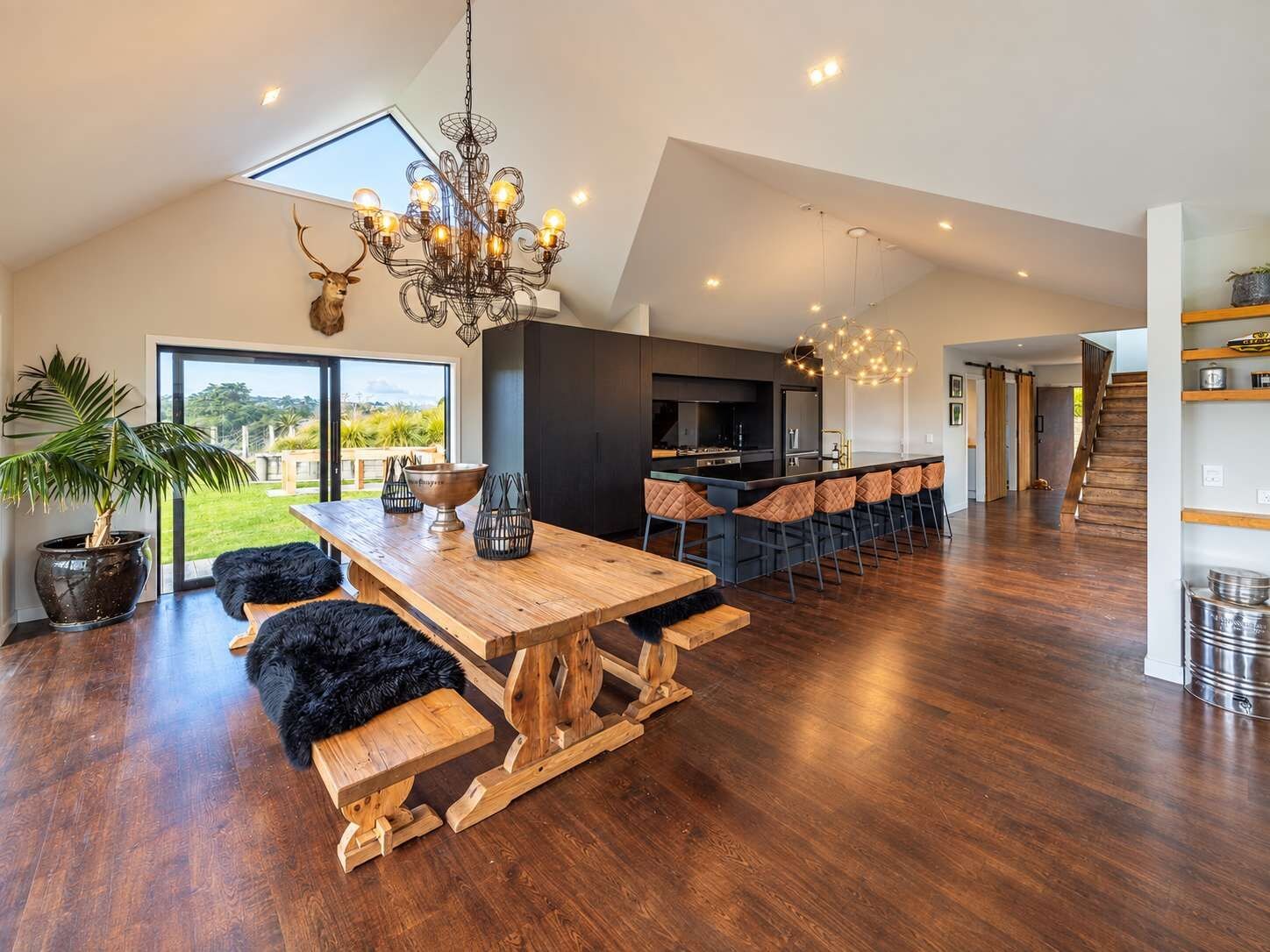 A spacious kitchen with a large island, a dining area with wooden benches, and a chandelier.