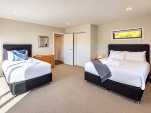 Ein Hotelzimmer mit zwei Betten, einem Holzschrank, einem Spiegel und einer Tür zu einem anderen Raum.