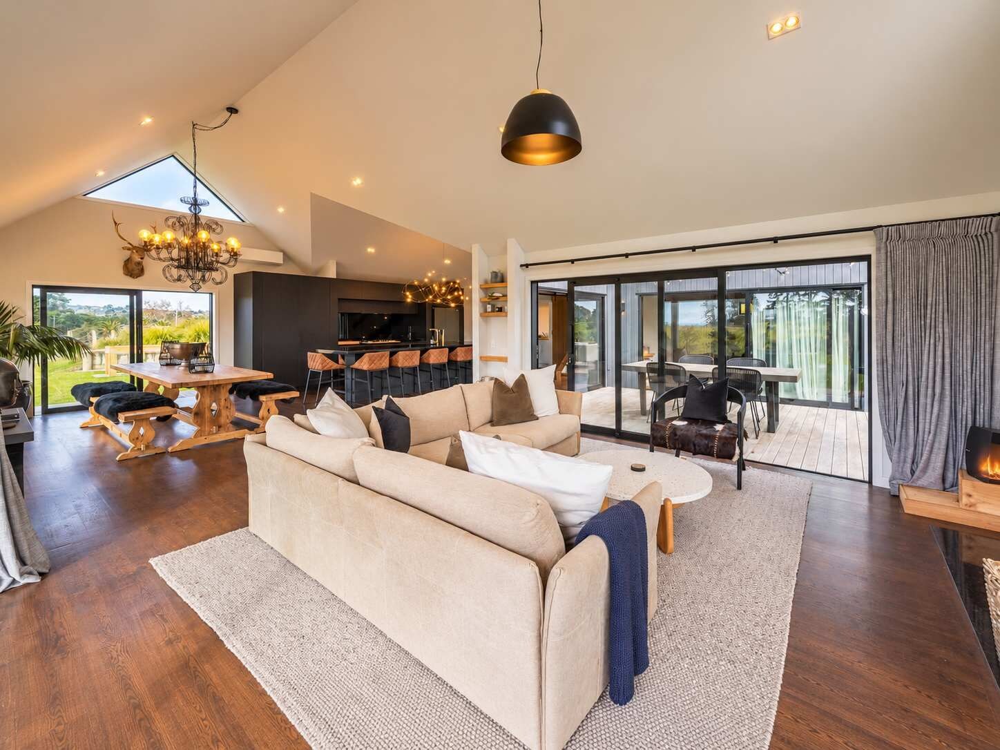 A spacious living area with a large sofa, a dining table, and a kitchen in the background.