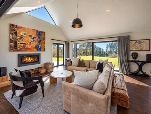 A modern living room with a fireplace, a large window, and a view of the outdoors.