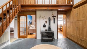 A spacious room with a wooden staircase, a black stove, and wooden cabinets.