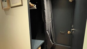 A small, dark room with a wooden floor, a black door, and a shelf with a few items. - National Assembly Orsay Museum (Paris)