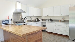 A modern kitchen with white cabinets, a wooden countertop, a stainless steel range hood, and a built-in oven. - Millside, Bosham -  a bungalow that sleeps 4 guests  in 1 bedroom (Bosham)