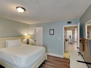 Un dormitorio con cama, lámpara de noche y puerta que da al baño.