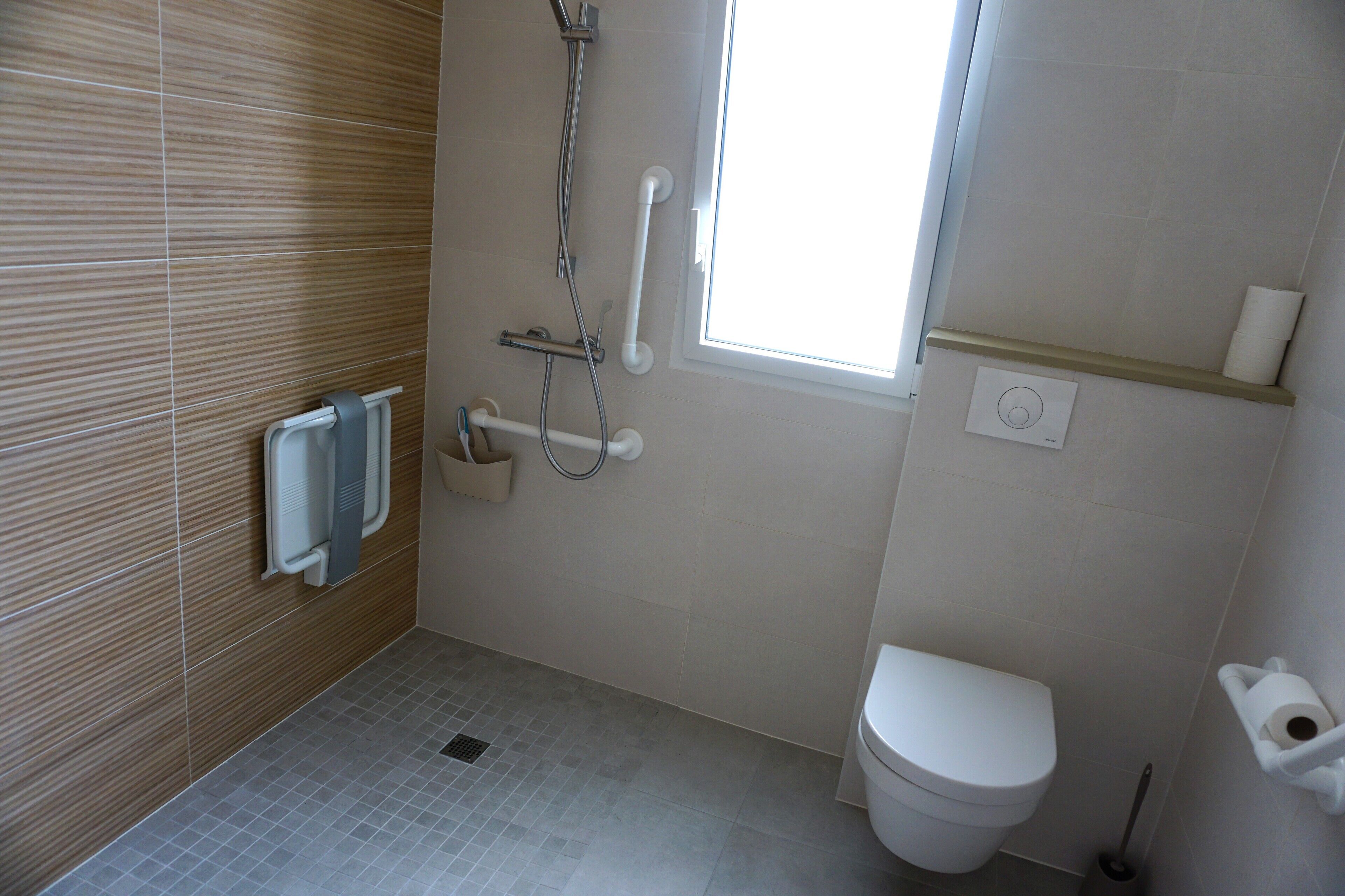 Une salle de bain avec des toilettes, une douche et une fenêtre.