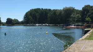 Ein ruhiger Fluss mit Booten, einem Anlegesteg und Bäumen im Hintergrund.