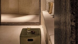 A minimalist bathroom with a bathtub, a small stool with a glass, and a bench with cushions. - Norman Hôtel & spa - Paris Champs-elysées (Paris)