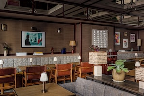 A restaurant with wooden furniture, a counter with a menu, and wall art. - Norman Hôtel & spa - Paris Champs-elysées (Paris)