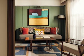 Une chambre d’hôtel moderne, équipée d’un canapé, d’une table basse et d’une lampe.