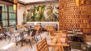 An outdoor seating area with tables and chairs, a wooden wall with a geometric pattern, and hanging pendant lights. - Norman Hôtel & spa - Paris Champs-elysées (Paris)