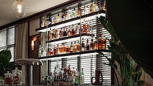 A bar area with shelves of bottles, a bar counter, and seating with tables and chairs. - Norman Hôtel & spa - Paris Champs-elysées (Paris)