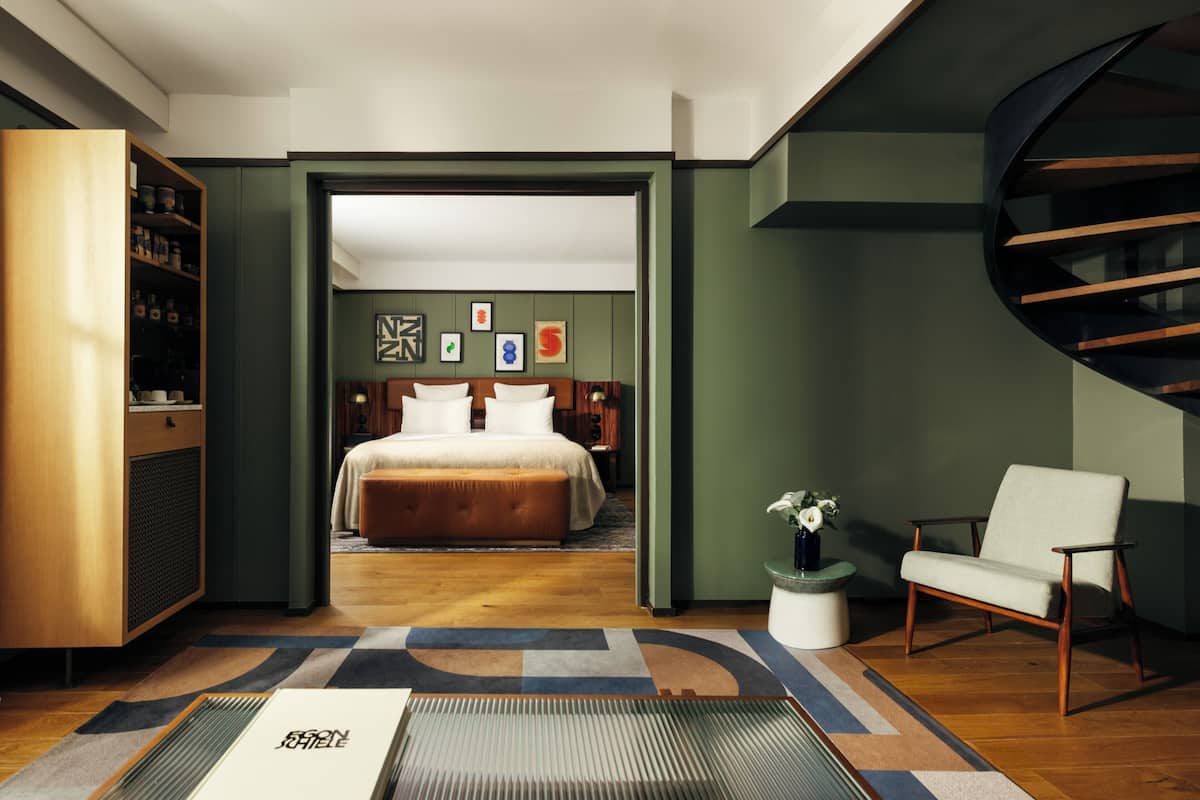 Una habitación de hotel moderna con una cama grande, una zona de estar y una escalera de caracol.