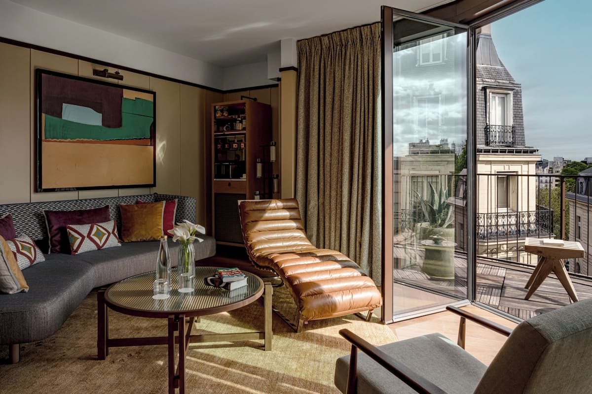 Una sala de estar moderna con un sofá, una chaise longue, una mesa de centro y una estantería.